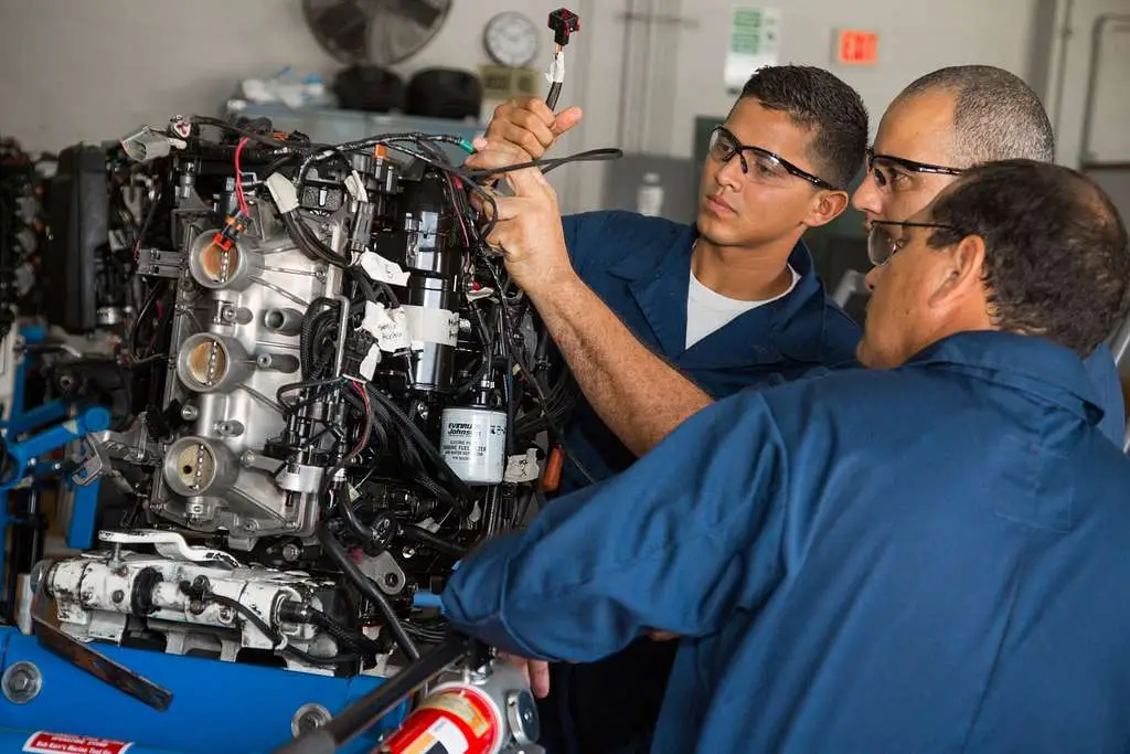 Technicians working on an outboard motor in a repair shop