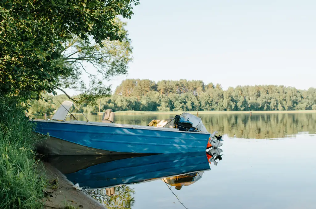 Fishing boat with an outboard motor beached on a lake shore