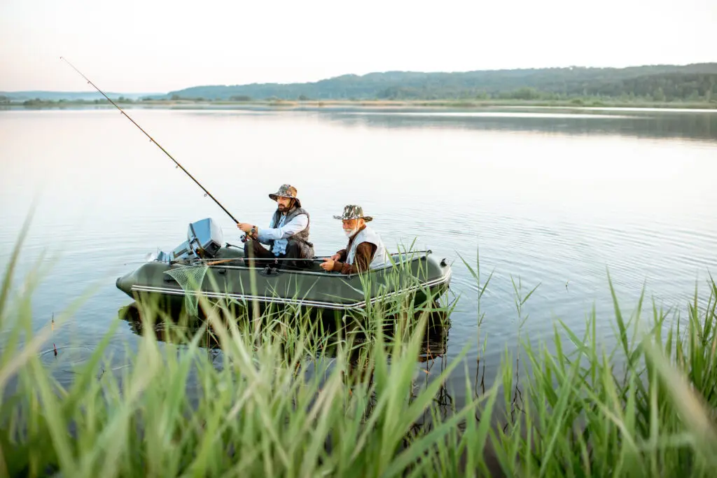 Grandfather and grandson fishing from a boat on a lake